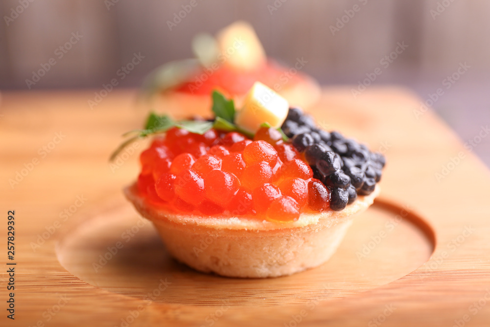Tasty tartlet with caviar on wooden board, closeup Tasty tartlet with caviar on wooden board, closeup