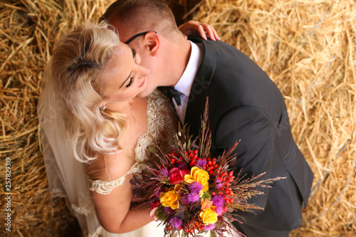 Beautiful wedding couple posing near hay photo