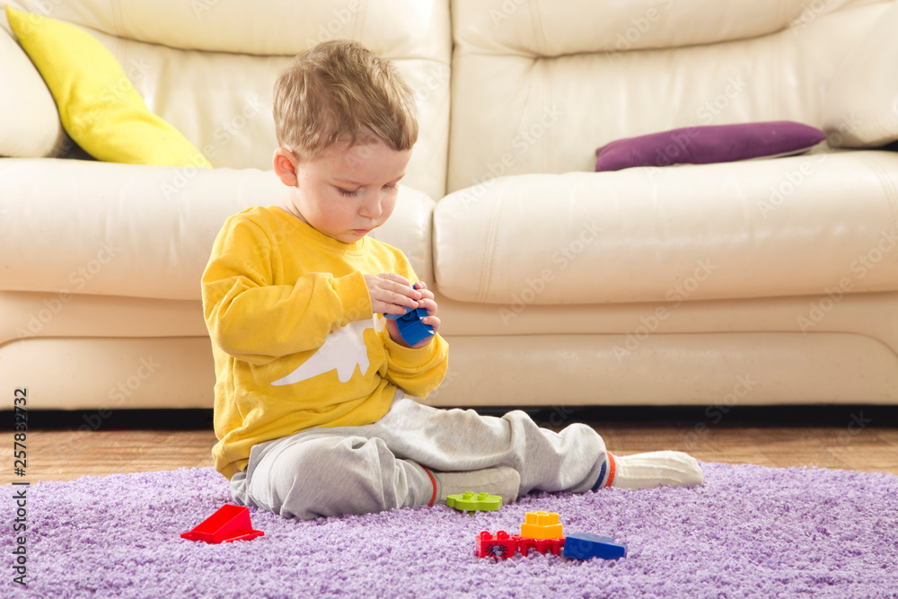 Child plays in designer. Cute boy playing alone with toys. Child plays in designer. Cute boy playing alone with toys.