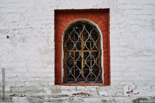 Window with grill on the background of an old brick wall © Oleg