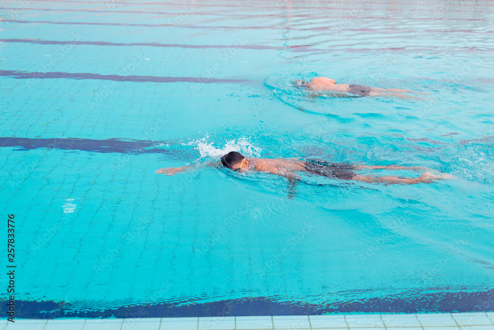 Young man swimming in the swimming pool . Fit swimmer training in the swimming pool. Professional male swimmer inside swimming pool. 