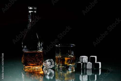 glasses made from whiskey on a glass table are isolated on a black background, special stones for whiskey. glass objects