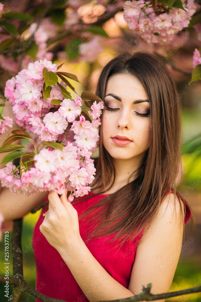 Portrait of beutiful girl in sakura tree. Sakura flowers surround the girl. Sakura branch by her face. Japanese tree Portrait of beutiful girl in sakura tree. Sakura flowers surround the girl. Sakura branch by her face. Japanese tree