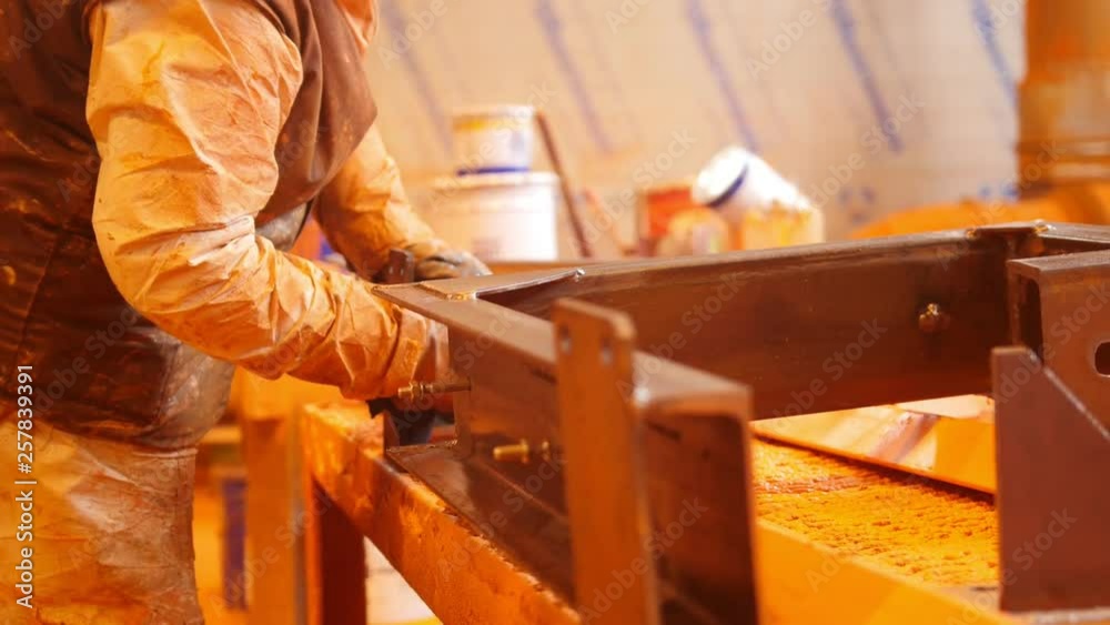 Construction plant. A man cleaning the surface out of the paint Construction plant. A man cleaning the surface out of the paint