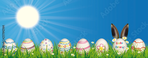 Frohe Ostern Banner mit bunten Ostereiern, Hasenohren und einem blauen Himmel mit strahlenden Sonne