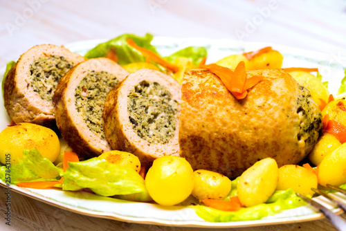 Meatloaf with spinach stuffing served with fried potatoes and carrot. photo