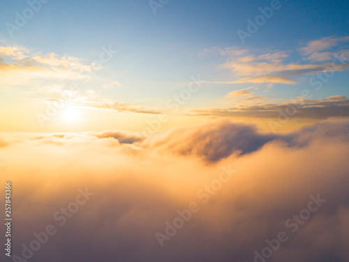 Aerial view White clouds in blue sky. Top view. View from drone. Aerial bird's eye view. Aerial top view cloudscape. Texture of clouds. View from above. Sunrise or sunset over clouds © Aleksei