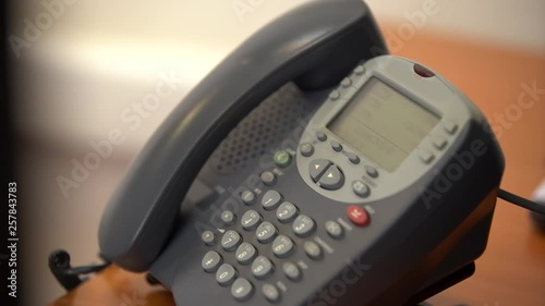The woman puts down the old wired phone with buttons, then picks up the phone again and dials the phone number, then hangs up, close-up