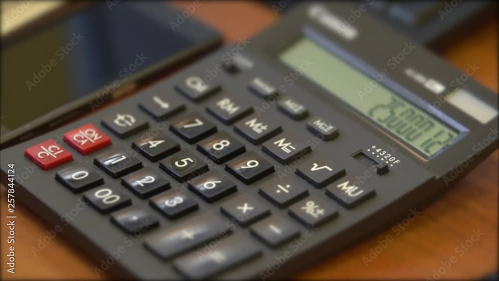 The female hand is gaining a number, doing calculations on the calculator, close-up The female hand is gaining a number, doing calculations on the calculator, close-up