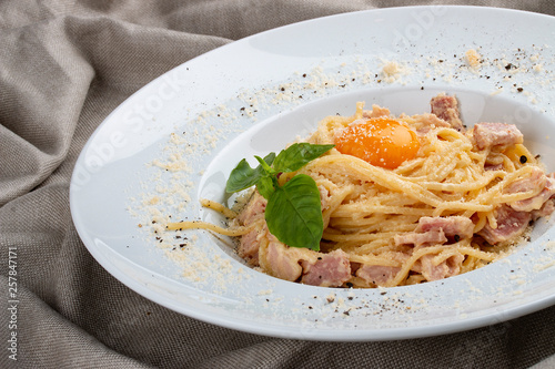 Spaghetti Carbonara on white plate on textile background