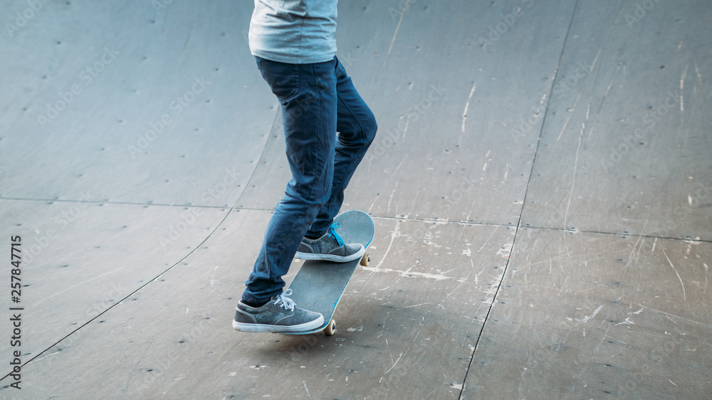 Urban skater in action. Practice time. Man riding skateboard. Legs in jeans. Cropped shot. Skate park ramp. Copy space. Urban skater in action. Practice time. Man riding skateboard. Legs in jeans. Cropped shot. Skate park ramp. Copy space.