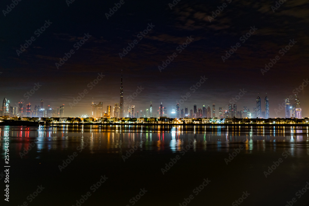 Dubai in night city lights or dusk. Dawn over Burj Khalifa. Nightly Dubai downtown. View from sea to Dubai quay