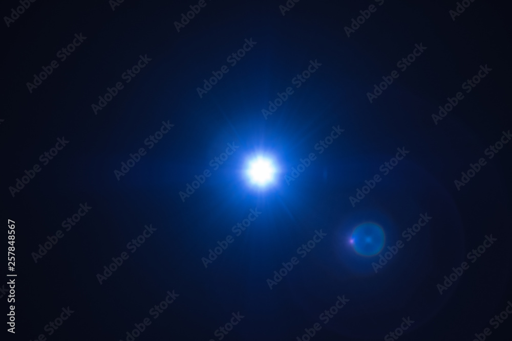 Blue flash spark on black background. Lens flare effect. Defocused spotlight glow