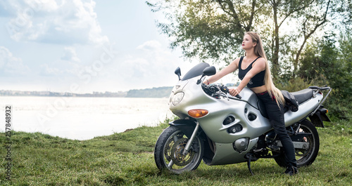 Biker woman with motorcycle rest near a pond