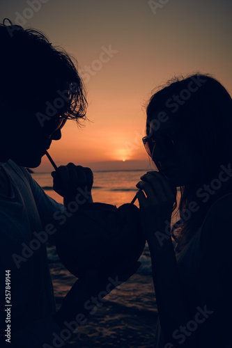 Couple drinking cocnut juice while watching the sunset over the ocean in Bali, Indonesia.