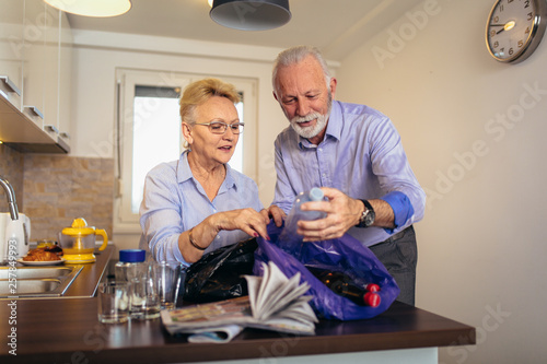 Obraz na płótnie Senior couple separating recyclable trash at home