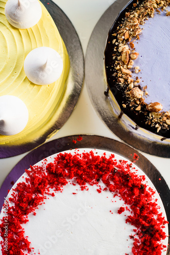 Assorted cakes: red velvet, purple nut cake and yellow cake decorated with meringue close up.  top view. flat lay photo