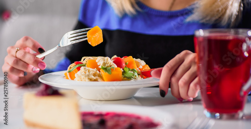 girl eating pasta with vegetables in a restaurant. Blurred dessert on background. light background. close-up. space.