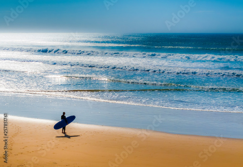 Photography Lone surfer on beach watching the incoming waves