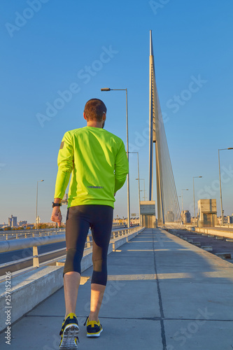 Fototapeta Naklejka Na Ścianę i Meble -  Sportsman working out / jogging on a big city urban bridge.