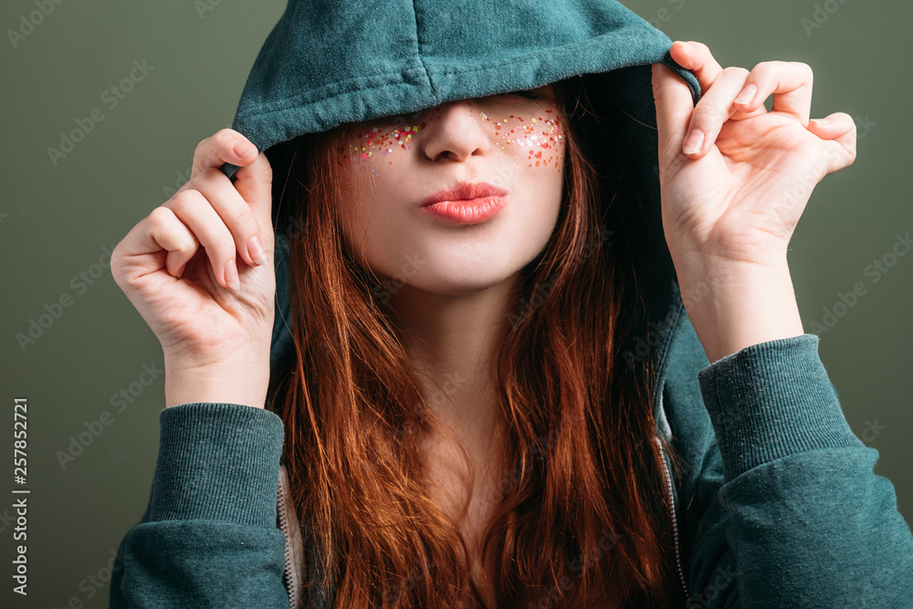 Cute young woman portrait. Youth freedom fun. Flirty mood. Pout lips. Eyes hidden by hood. Cute young woman portrait. Youth freedom fun. Flirty mood. Pout lips. Eyes hidden by hood.