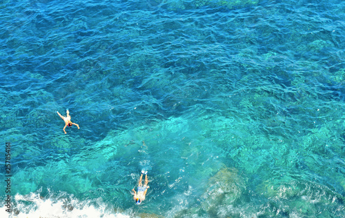 Two young men swimm and snorkeling inside paradise clear torquoise blue water in Favignana island, Bue Marino Beach, Sicily South Italy.
