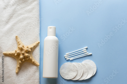 flat lay composition with Bath skincare products. milk, cotton pads, sea star . blue spa background. top view