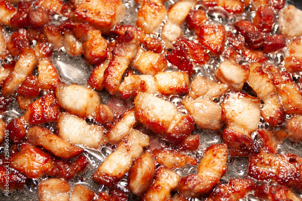 Chopped bits of bacon frying in a skillet