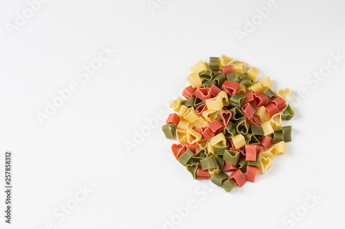 on a white background pasta in the form of hearts (red, green and yellow)