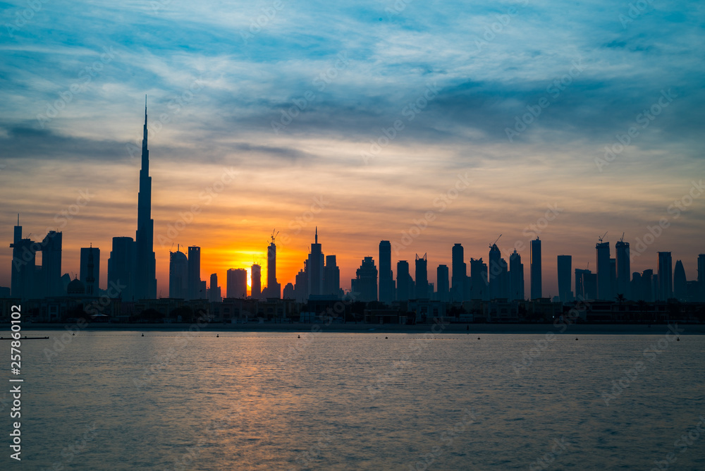 Sunrise in Dubai, dawn over Burj Khalifa. Morning in Dubai, Sun over buildings. Solar path on sea comes from Burj Khalifa