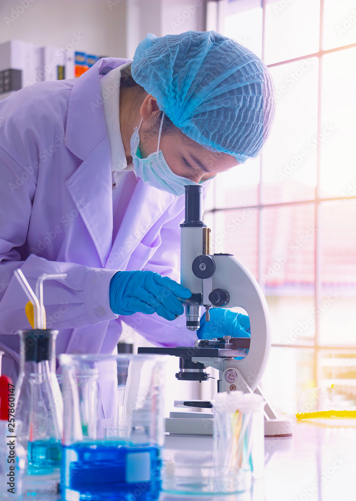 Young Asia woman scientist working in laboratory.She is looking microscope.She is trying and research with red and blue test tube. Experiment , chemical Photo concept develop and medicine. Young Asia woman scientist working in laboratory.She is looking microscope.She is trying and research with red and blue test tube. Experiment , chemical Photo concept develop and medicine.