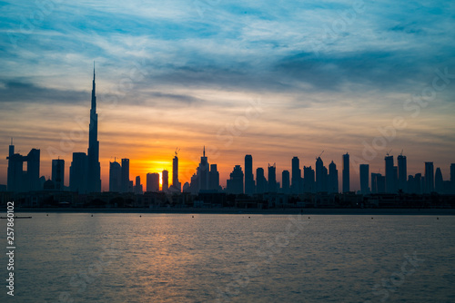 Sunrise in Dubai, dawn over Burj Khalifa. Morning in Dubai, Sun over buildings. Solar path on sea comes from Burj Khalifa © HLEB