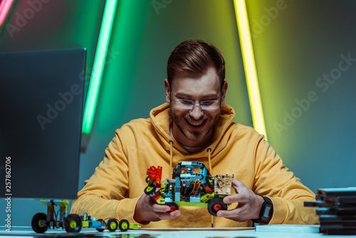 Fényképezés smiling and handsome man in glasses playing with toy constructor