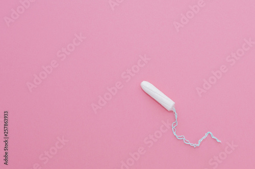 Cotton tampon on pink background. Menstrual cycle, feminine care, menstruation and intimate products concept with internal tampon isolated on pink background