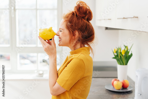 Smiling woman playing with piggy bank photo