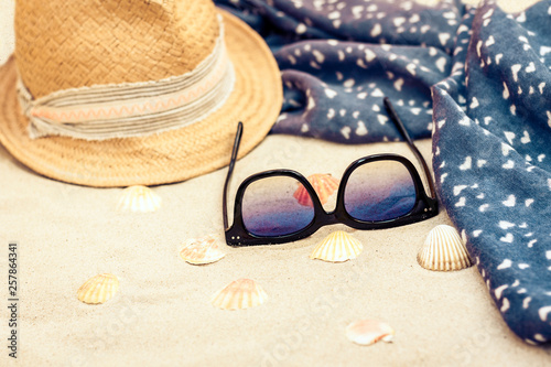 Straw hat, cover-up beachwear wrap and sun glasses on a tropical beach .