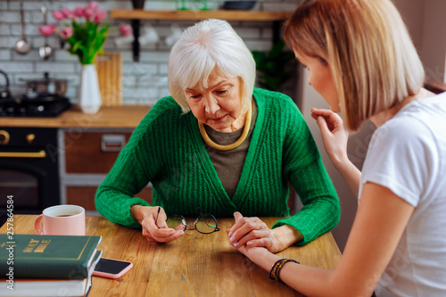 Young-adult good-looking woman cheering up delightful upset silver-haired female photo