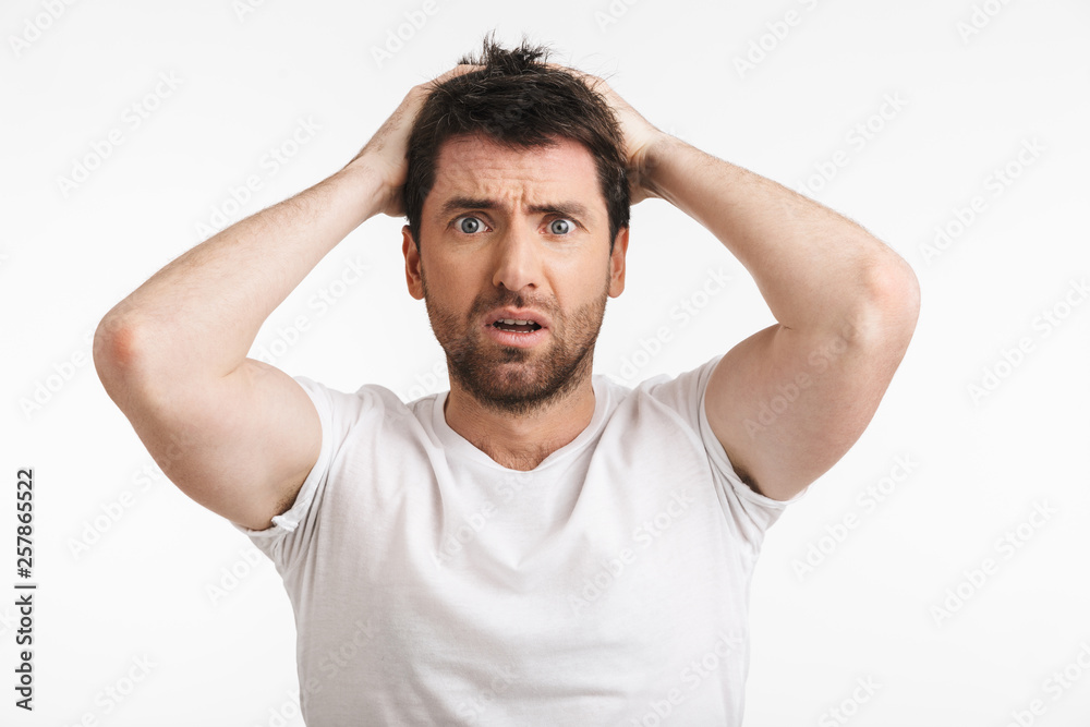 Image of muscular man 30s with bristle in casual t-shirt frowning and grabbing head Image of muscular man 30s with bristle in casual t-shirt frowning and grabbing head