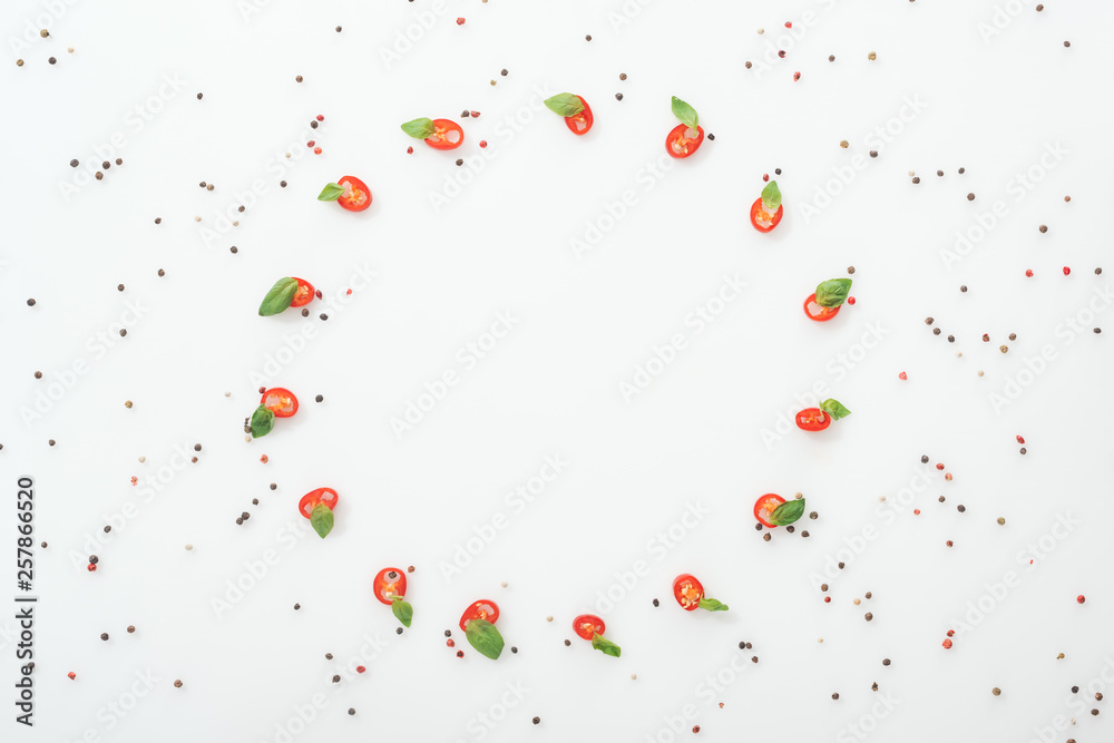 flat lay with spices and sliced chili peppers with basil leaves on white background with copy space