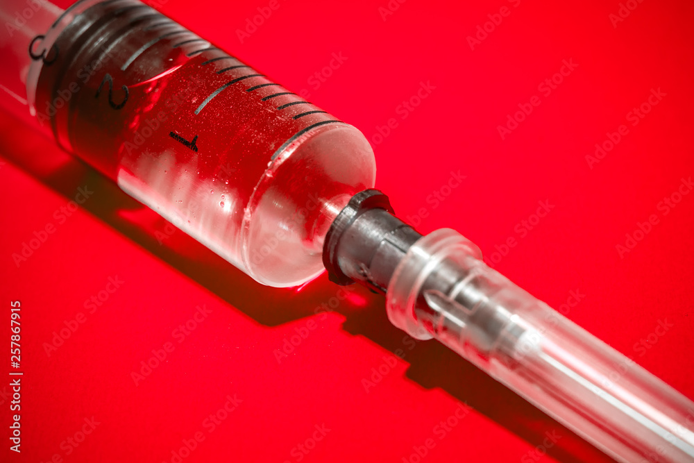 Empty syringe on red background, close up. Theme drug addiction Empty syringe on red background, close up. Theme drug addiction