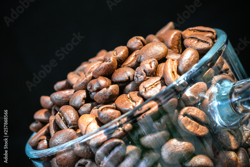 glass transparent cup with coffee beans inside close-up, in a low key