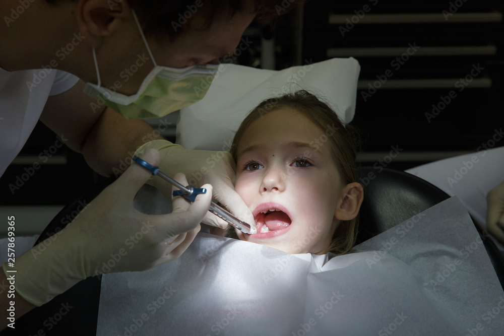 Scared little girl at dentist office, getting local anesthesia