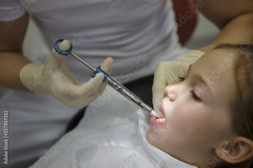 Obraz na płótnie Scared little girl at dentist office, getting local anesthesia injection into gums, dentist numbing gums for dental work. w salonie