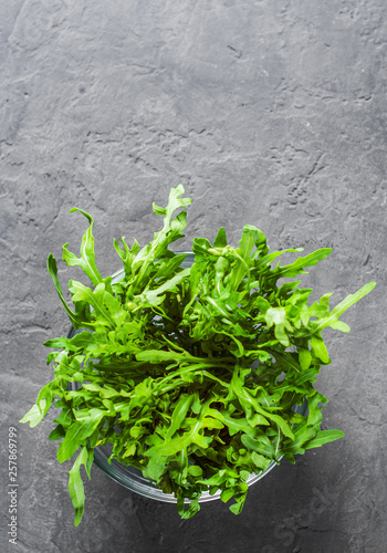 fresh arugula salad in glass bowl on Dark grey black slate background © pavel siamionov