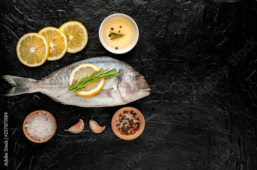 two fresh raw Dorado fish with spices and olive oil on a stone background.