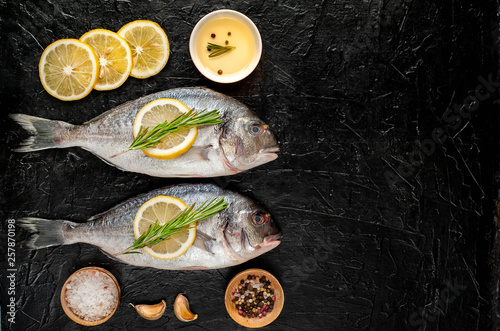 two fresh raw Dorado fish with spices and olive oil on a stone background.