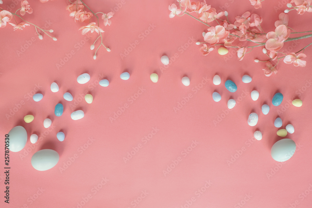 Pastel Easter Eggs Malt Candy and Flowers over a Coral Colored Background Pastel Easter Eggs Malt Candy and Flowers over a Coral Colored Background