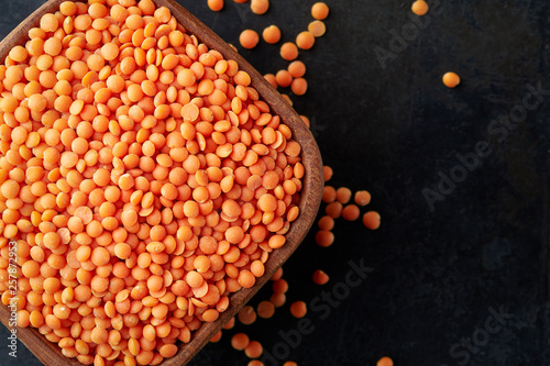 Raw uncooked red lentils (lens culinaris) in wooden bowl. Top view with copy space