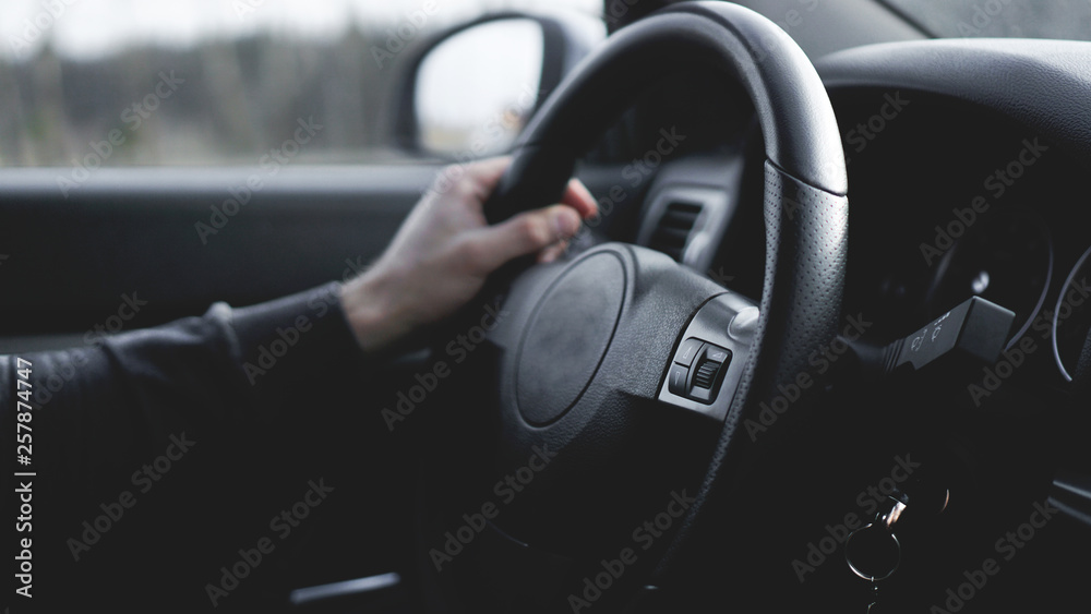 Interior view of car with black salon. Close-up Of A Man Hands Holding Steering Wheel While Driving Car