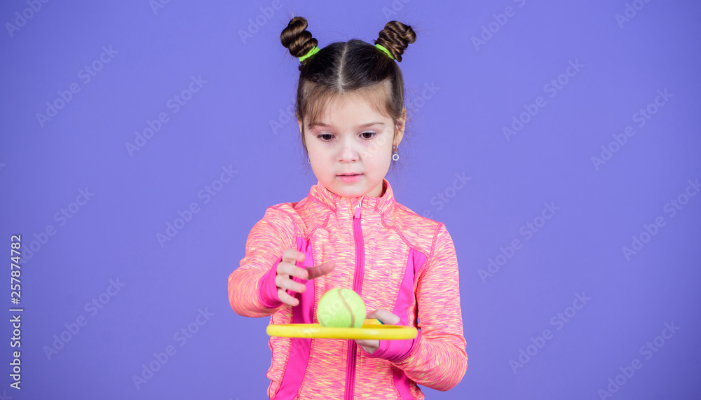Little baby sporty costume play tennis game. Teach me how to play tennis. Girl  cute child double bun hairstyle tennis player. Childhood and active games.  Sport upbringing. Small cutie likes tennis Stock
